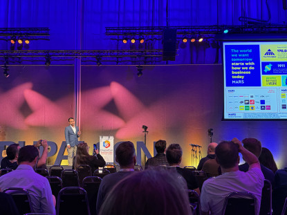 De vertegenwoordiger van Mars praat het publiek door een slide in zijn presentatie.