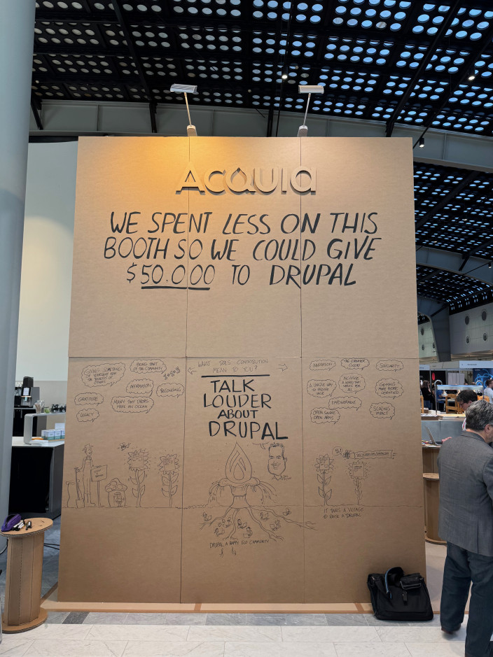 De beursstand van Acquia, opgetrokken uit karton, met het opschrift "We spent less on this booth so we could give $50.000 to Drupal."